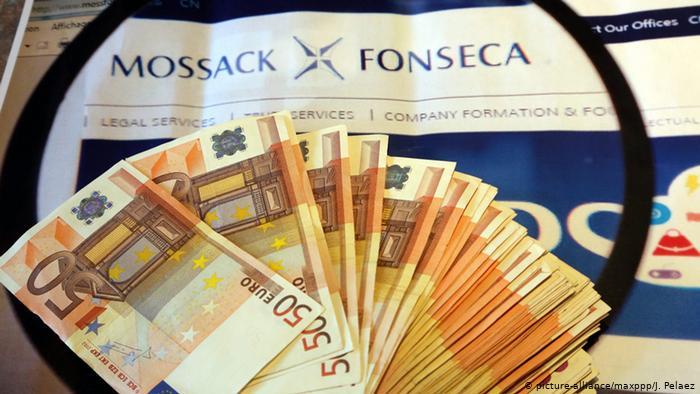 Символ коррупции - пачка банкнот на фоне сообщения в газете о расследовании архивов панамской фирмы Mossack Fonseca. 
