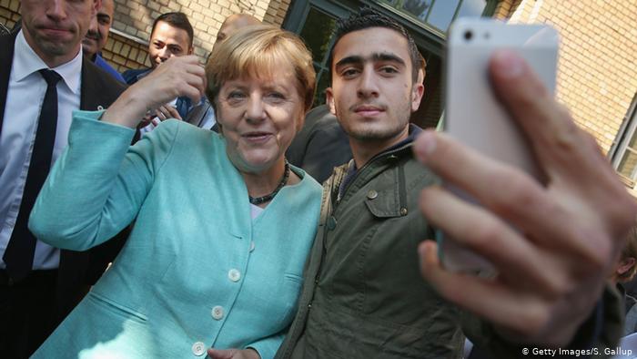 Ангела Меркель 9 сентября 2015 года фотографируется в Берлине с сирийским беженцем Анасом Модамани 