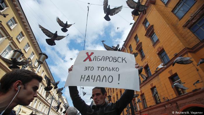 Один из участников акции в поддержку хабаровчан в Санкт-Петербурге держит в руках плакат с надписью Хабаровск - это только начало!, а над его гловой кружат голуби.