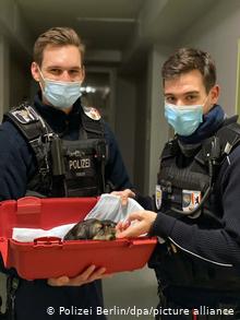 Двое полицейских держат корзину с щенком