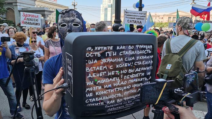 Участник акции держит телевизор, на экран которого нанесены цитаты государственной пропаганды