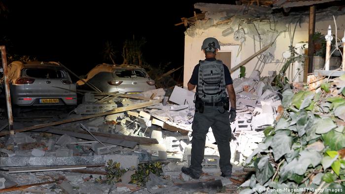 Сотрудник спецслужб Израиля обследует руины дома в городе Йехуд