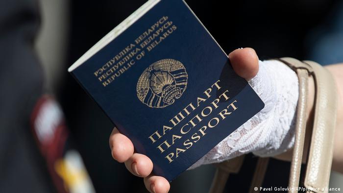 Женщина держит в руке паспорт Беларуси