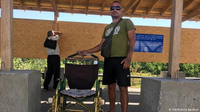 Мужчина, за деньги довозящий людей от моста к украинскому КПВВ в инвалидной коляске