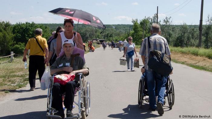 Пожилые люди и инвалиды пересекают КПВВ Станция Луганская