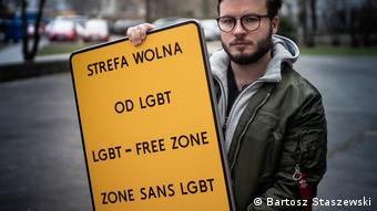 Бартош Сташевски показывает табличку, на которой написано зона, свободная от ЛГБТ