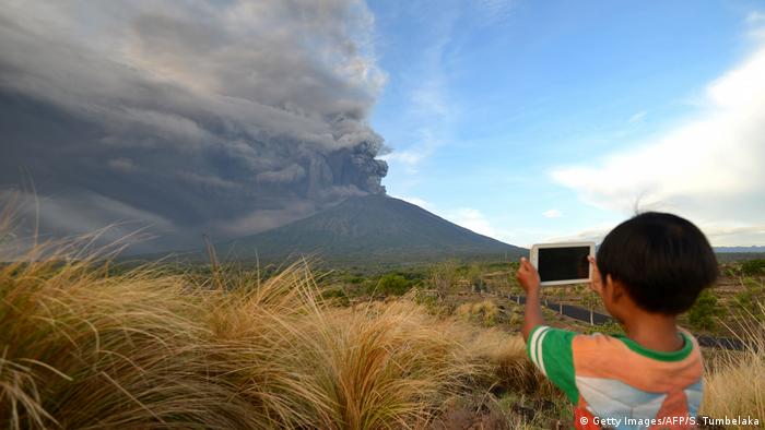 Мальчик фотографирует вулкан на смартфон