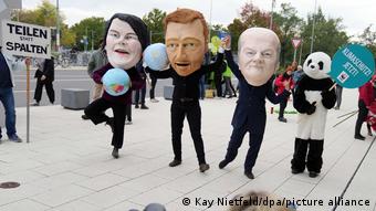 Демонстранты в масках Анналены Бербок, Кристиана Линднера и Олафа Шольца
