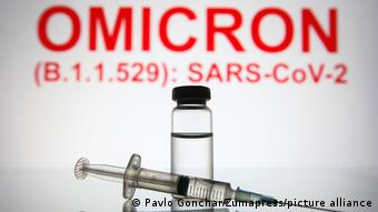 Ампула с вакциной и шприц на фоне названия нового варианта коронавируса - омикрон (B.1.1.529)