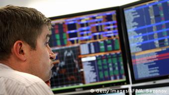 Мужчина на фоне табло с биржевыми индексами 