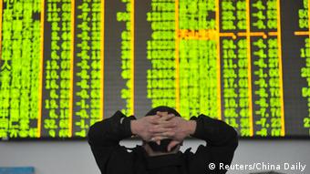 Китайский частный инвестор перед табло с биржевыми курсами