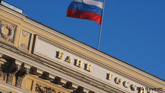 Флаг РФ над сфотографированным под наклоном зданием Банка России