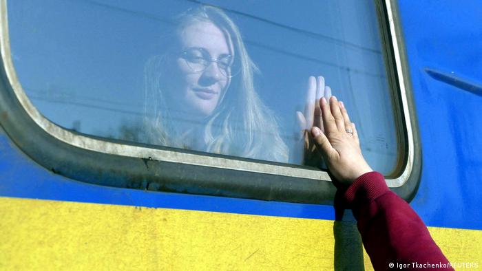 Женщина, находящаяся в вагоне поезда, прощается со своими родными на вокзале в Одессе, 25 апреля 2022 года