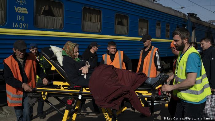 Спасатели помогают пожилой женщине сесть в поезд на вокзале в Покровске, 25 апреля 2022 года