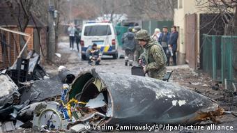Украинский военный изучает остатки сбитого самолета, 25 февраля 2022 года