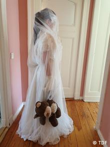 Девочка в свадебном платье с сплюшевым медвежонком в руке - символ принудительного брака