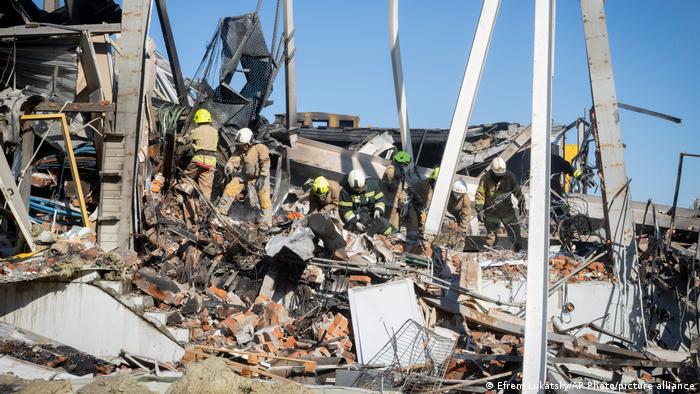 Пожарные разбирают развалины торгового центра Амстор в Кременчуге после попадания в него российской ракеты 