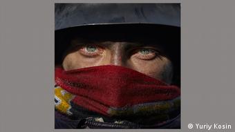 Солдат смотрит в объектив камеры, нижняя часть лица закрыта красным шарфом. Фотография Юрия Косина